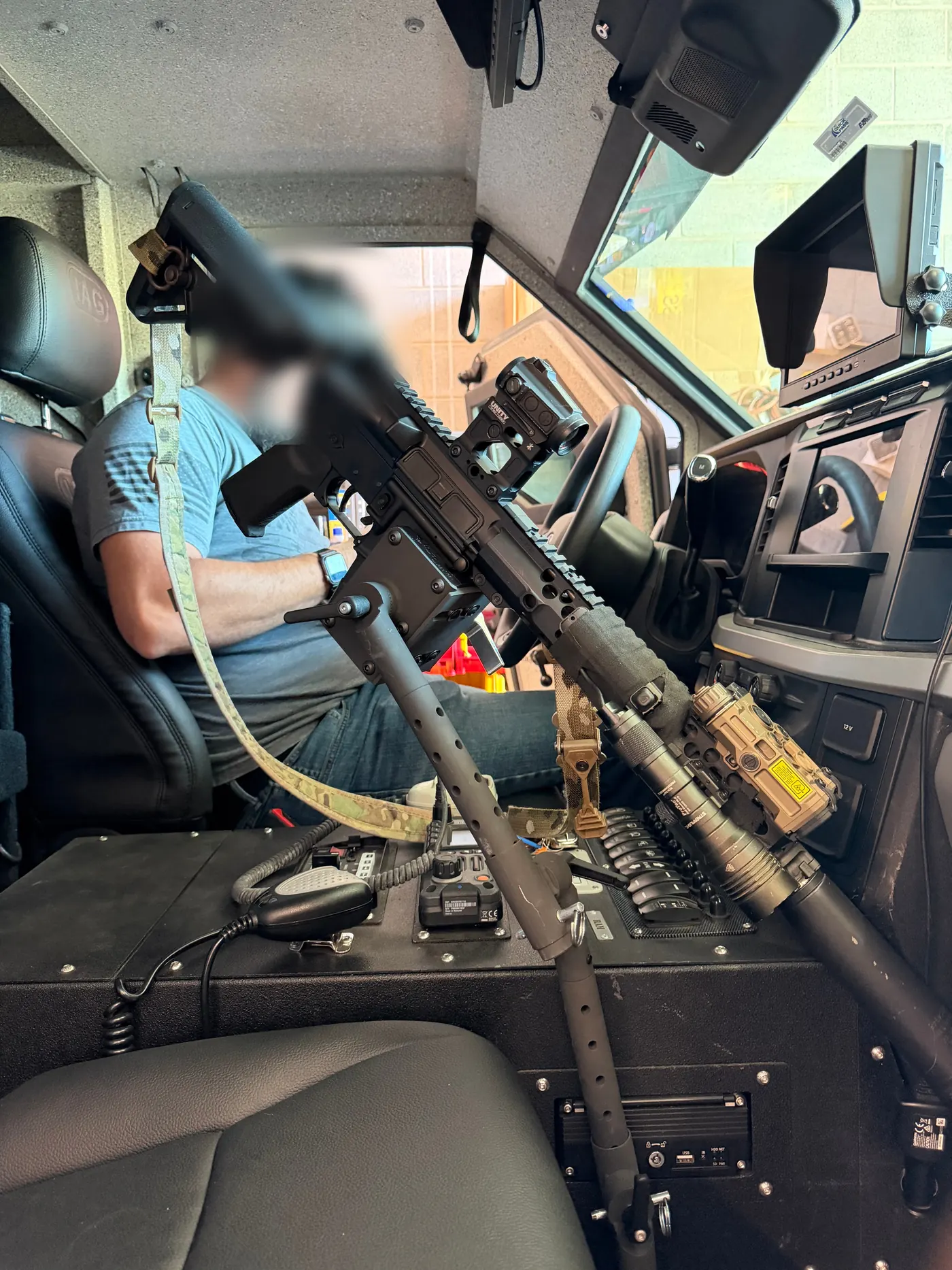 Close-up of an AR-pattern rifle with optic, light, and laser secured in the StandA.R.D. cradle inside the Sentinel cab